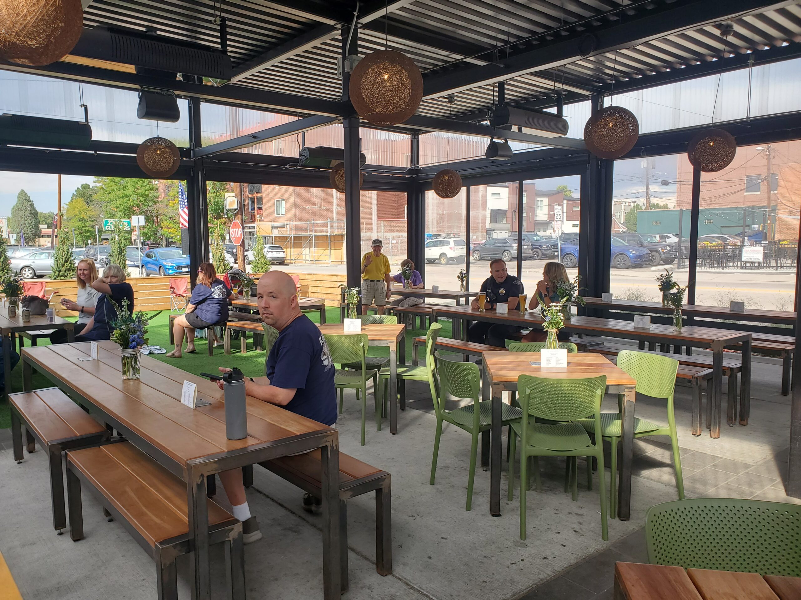 People dining in a spacious, open-air restaurant with green chairs and wooden tables.