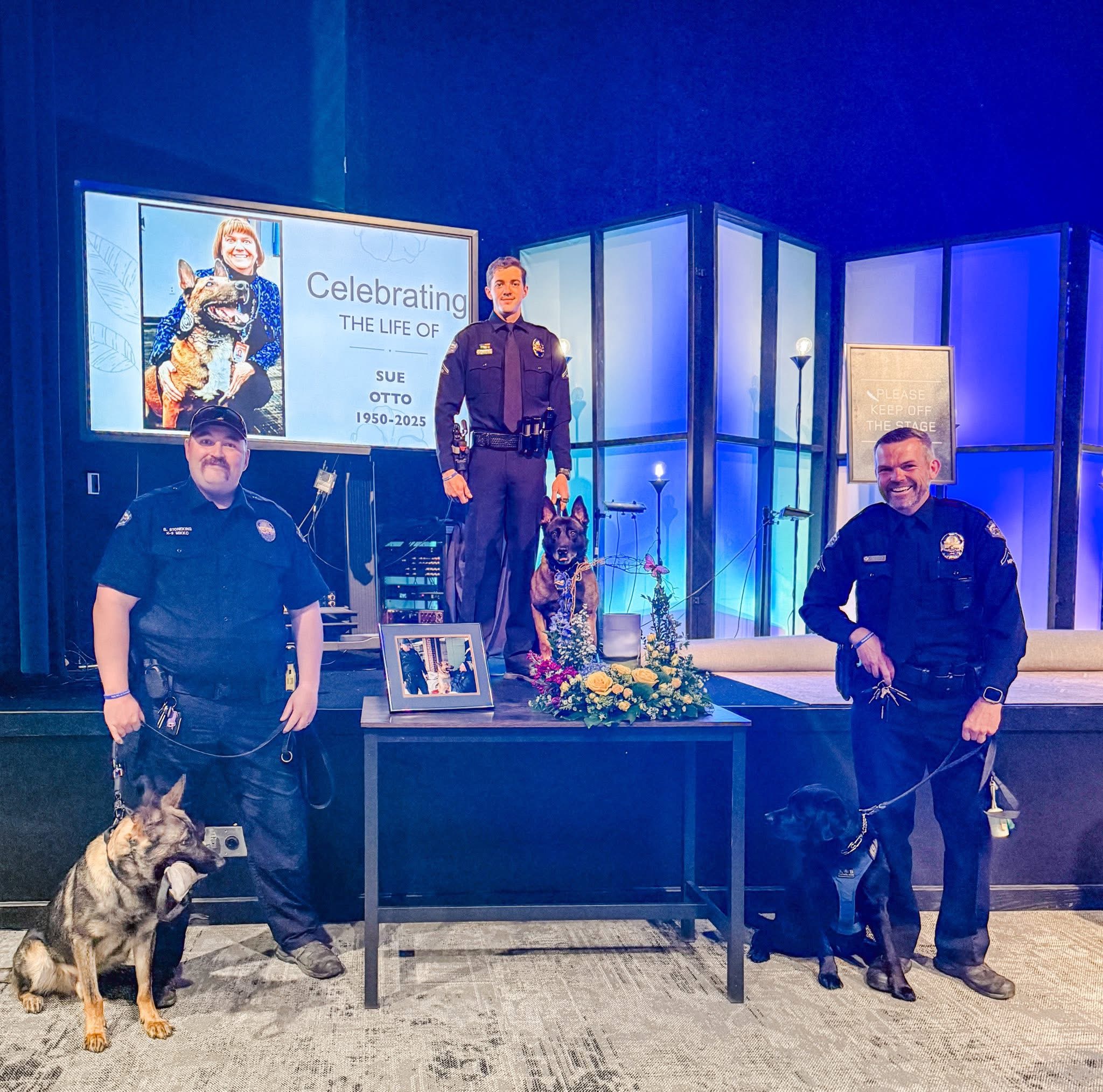 Two police officers with a police dog and a man on stage in a studio setting.