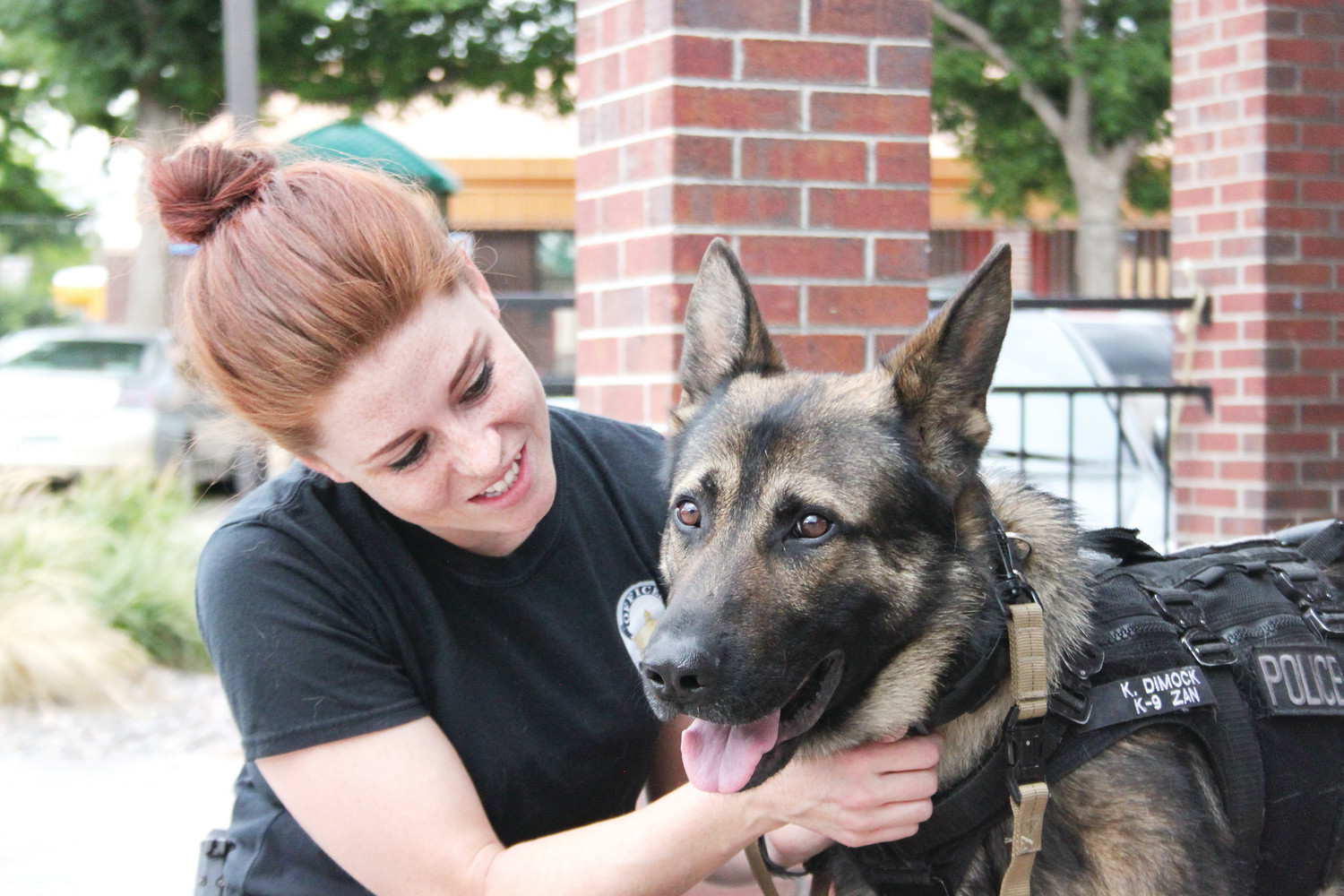 A woman happily embraces a German Shepherd outdoors.